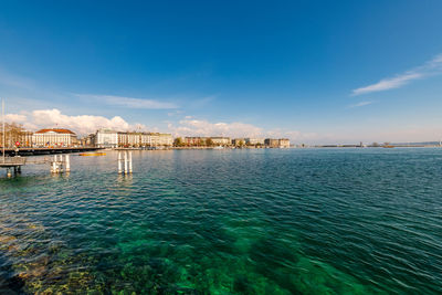 Scenic view of sea by buildings against blue sky