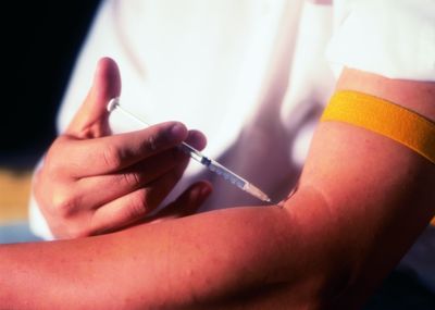 Midsection of person injecting with syringe