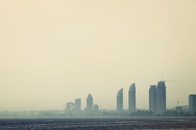 Sea by cityscape against sky