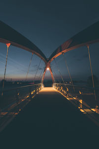 Illuminated suspension bridge over river against clear sky at night