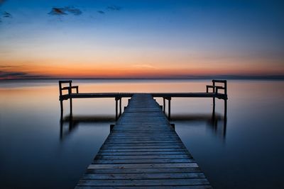 Pier over sea against sky during sunset