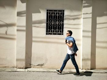 Full length of young man walking against building