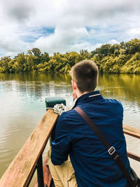 Young boy on the bow of a wooden boat having a drink