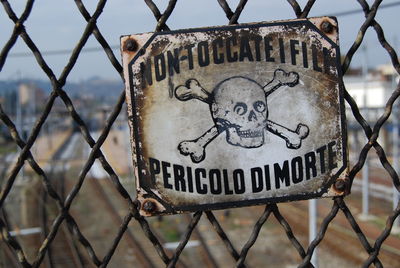 Close-up of old warning sign on chainlink fence