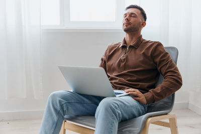 Young man using laptop while sitting on sofa at home