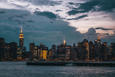 View of buildings at waterfront against cloudy sky