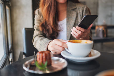 Midsection of woman holding coffee cup on table