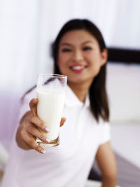 Smiling woman drinking milk at home