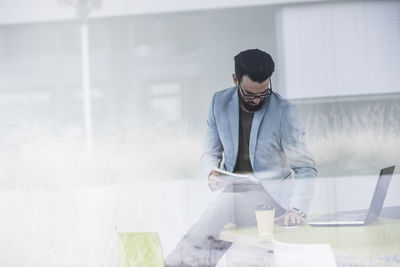 Young businessman sitting on desk, working