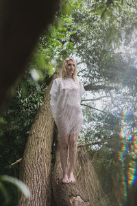 Woman standing by tree against plants