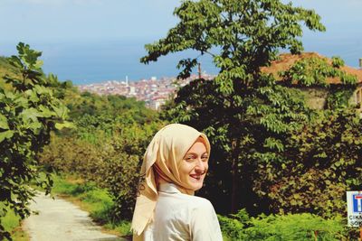 Portrait of smiling woman against trees