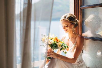 Woman holding flower vase against window