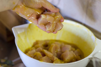 Close-up of woman holding meat over container