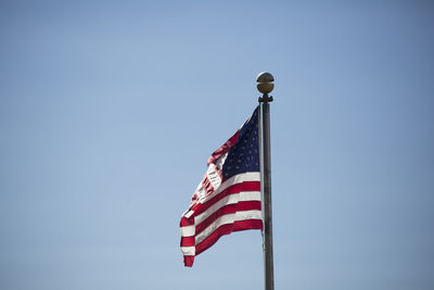 Low angle view of flags against clear blue sky