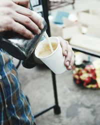 Midsection of barista making coffee in disposable cup at cafe