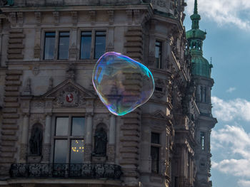 Low angle view of bubbles against rainbow in city