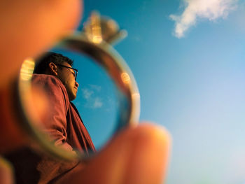 Low angle view of man holding blue sky