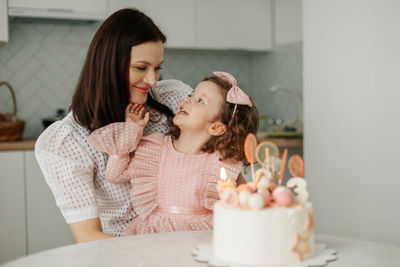 Portrait of a charming mother and daughter with a birthday cake in the kitchen. birthday, holiday