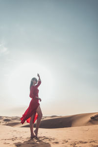 Full length of woman standing on beach against sky