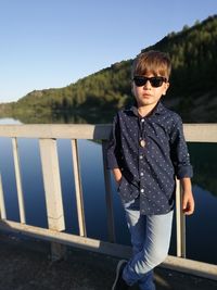 Man wearing sunglasses standing on mountain against clear sky