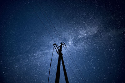 Low angle view of electricity pylon against sky at night