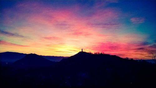 Silhouette mountains against dramatic sky during sunset