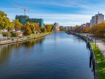 Bridge over river by buildings against sky