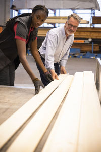 Male customer and saleswoman loading planks in trailer at hardware store