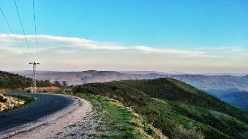 Road leading towards mountains against sky