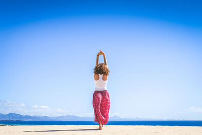 Rear view of woman standing at sea against sky