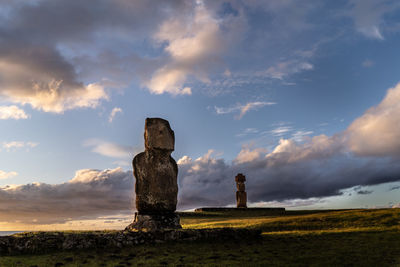 Stone structure on field against sky during sunset