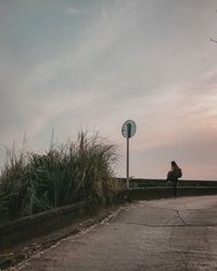 Man walking on road against sky
