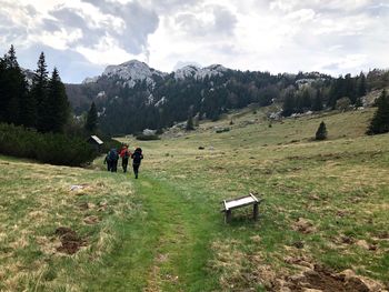 Rear view of people hiking on landscape against sky