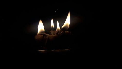 Close-up of lit candle against black background