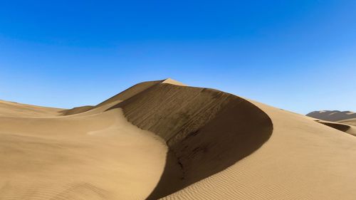 Scenic view of desert against clear blue sky