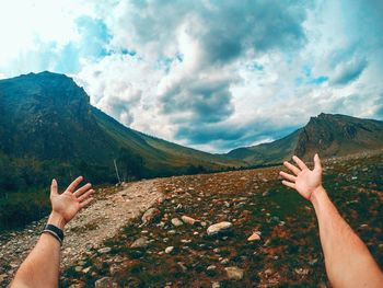 Midsection of woman with arms raised against mountains