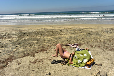 Woman lying on sand at beach against sky