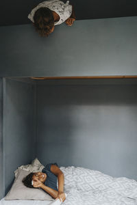 Boy talking with brother lying on bunkbed at home