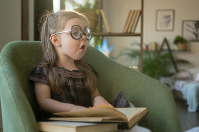 Cute girl yawing while sitting on sofa at home