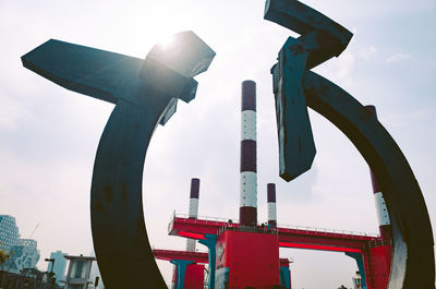 Low angle view of machinery against sky in city