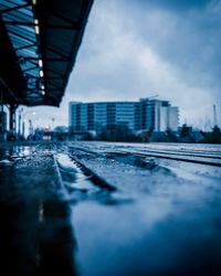 Surface level of railroad tracks by buildings in city against sky