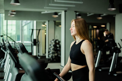 Happy athletic woman jogging on treadmills in a gym.