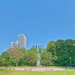 Statue by trees against clear blue sky