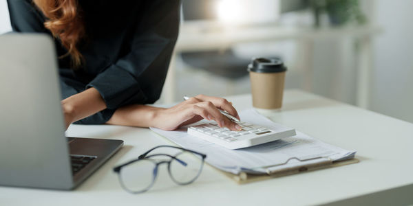 Midsection of woman using mobile phone on table