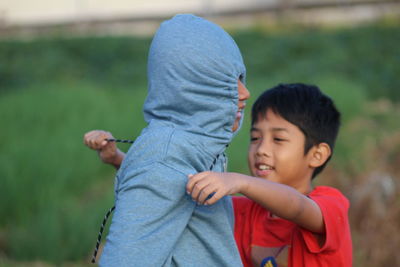 Boy tying friend with rope on field