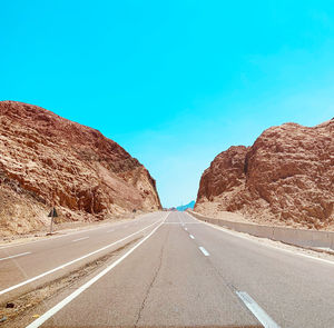 Surface level of empty road against blue sky