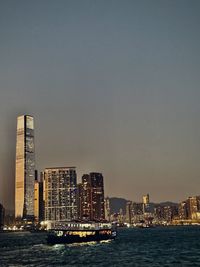 Sea by modern buildings against sky in city