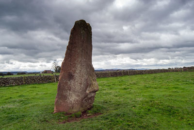 Stone wall on field against sky