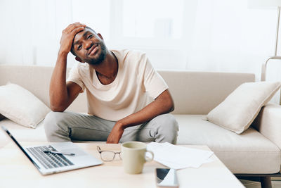 Young woman using laptop while sitting on sofa at home