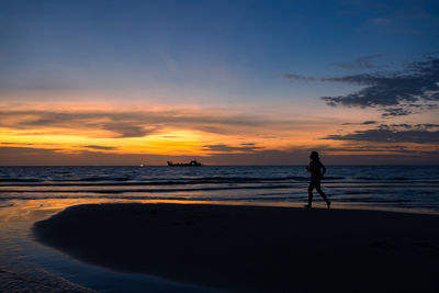 Silhouette of woman working out by running on beach at sunset. black and white color